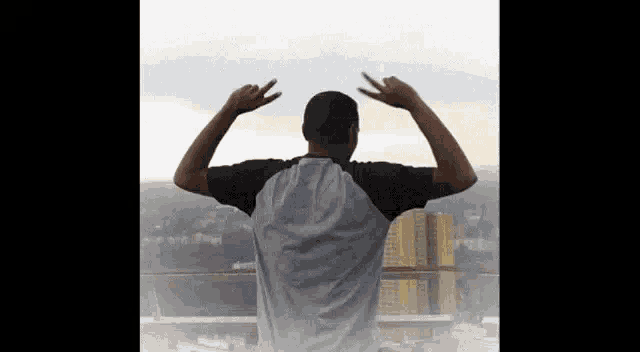 a man is standing on a balcony with his arms in the air and making a devil horns sign