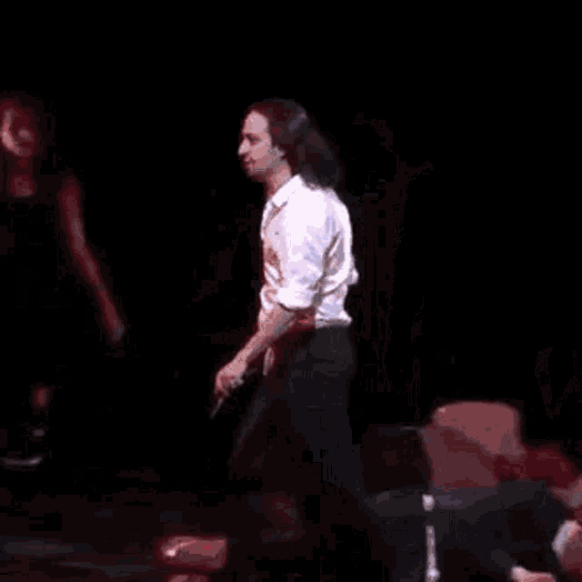 two men are standing next to each other on a stage while one of them sings into a microphone .