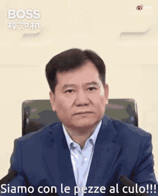 a man in a suit sits in front of a microphone and says boss