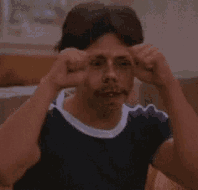 a man with a mustache is rubbing his forehead with his hands .