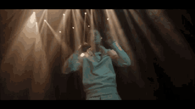 a man in a white shirt is standing in front of a stage with lights shining on him .