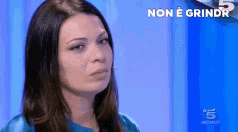 a woman in a blue shirt is on a television screen with the words non e grindr on it