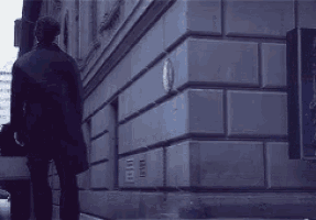 a man is walking down a sidewalk in front of a building with a sign that says new york