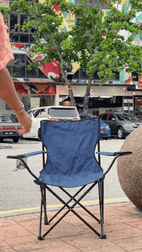 a blue folding chair is sitting on the sidewalk in front of a store