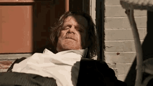 a man in a suit and tie is laying in a chair outside of a building .