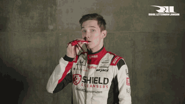 a man wearing a shield cleanser jacket holds a red object to his nose