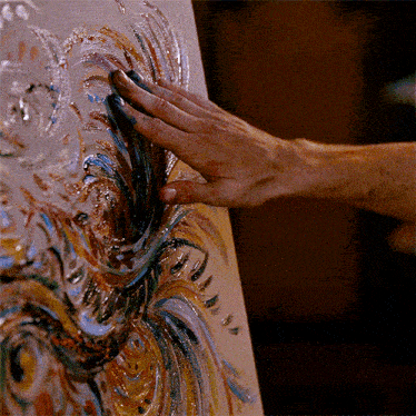 a close up of a person 's hand touching a painting on a canvas