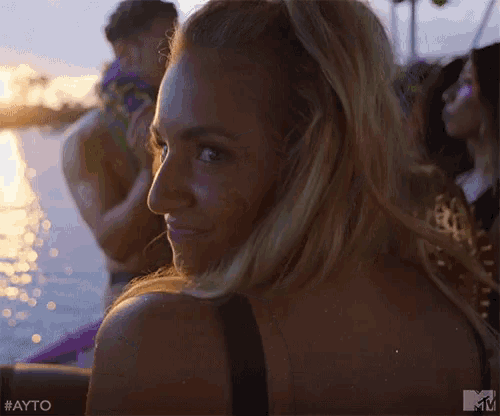 a woman is looking over her shoulder while sitting on a boat in the water .
