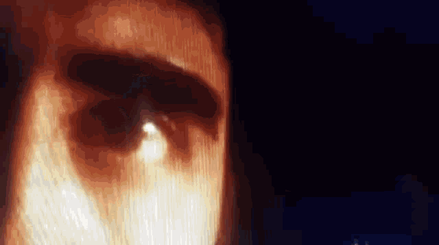a close up of a person 's eye in a dark room with a light shining through it .