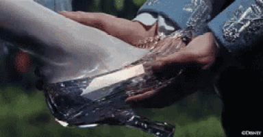 a man is putting a glass shoe on a woman 's feet .