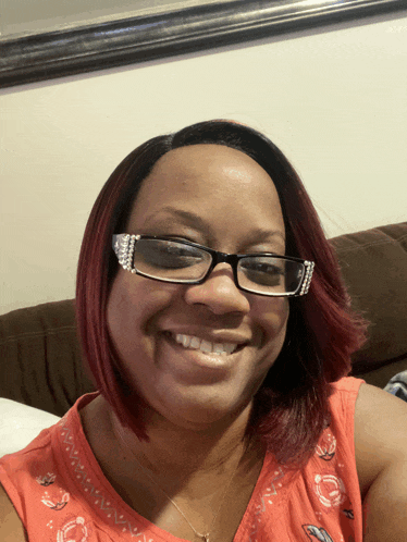 a woman wearing glasses and a red top smiles for the camera