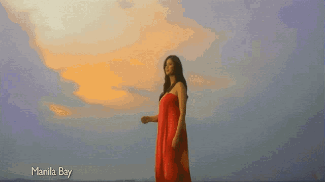 a woman in a red dress is standing on a beach with the words manila bay above her