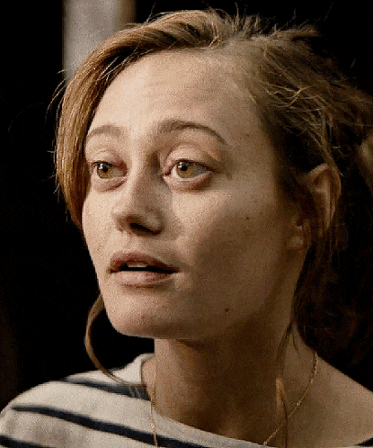 a close up of a woman 's face with a striped shirt and a necklace