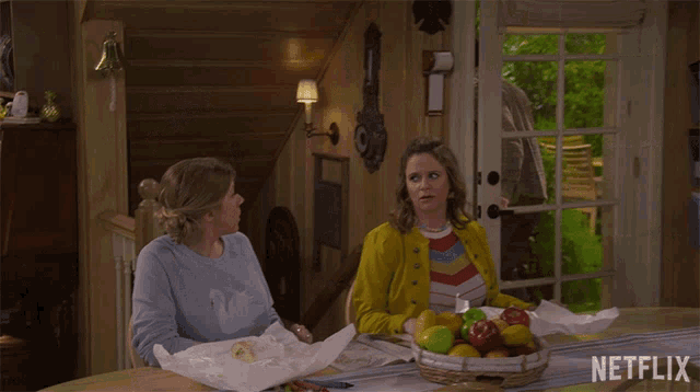 two women sit at a table with a netflix logo on the bottom right