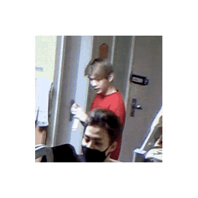 a man in a red shirt is standing next to another man in a room .
