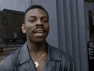 a man wearing a leather jacket and a gold necklace is smiling .