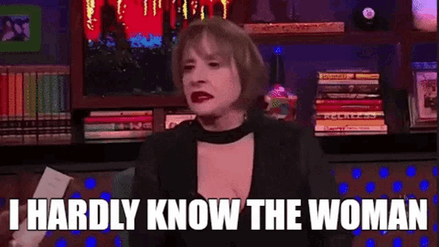 a woman is sitting in front of a bookshelf and talking to someone .