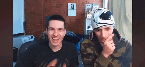two young men are sitting next to each other in a living room .