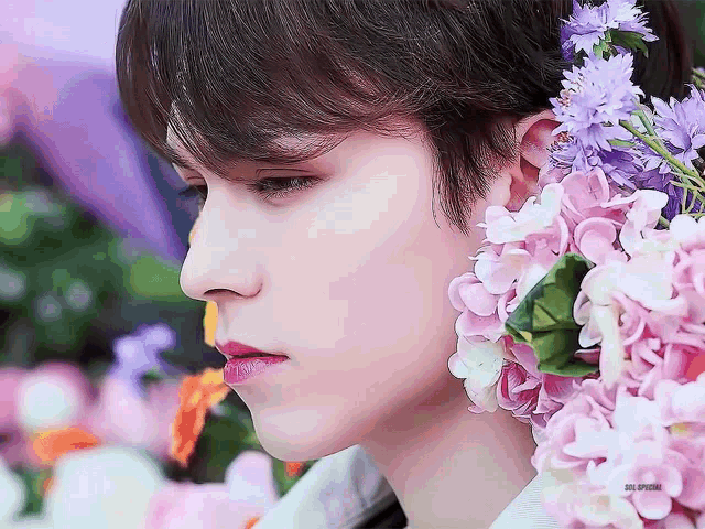 a close up of a person 's face with flowers on their ears