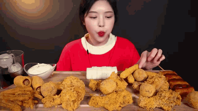 a woman in a red sweater is eating fried food