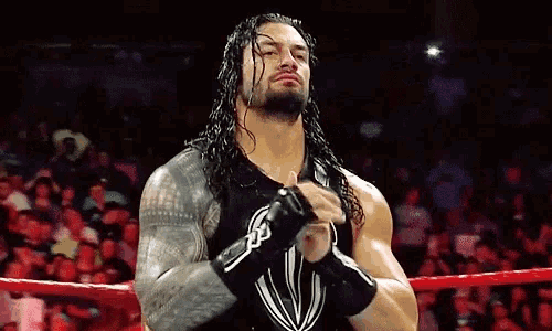 a wrestler with long hair is standing in a ring with his fist in the air