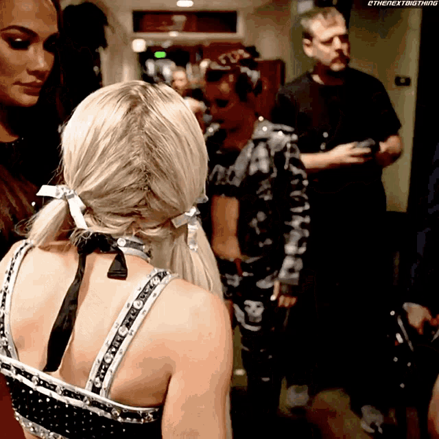 a woman in a braided ponytail stands in a hallway with a man in a skull shirt