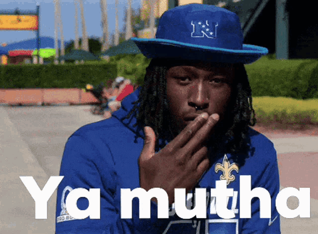 a man wearing a blue hat with the letter n on it covering his mouth
