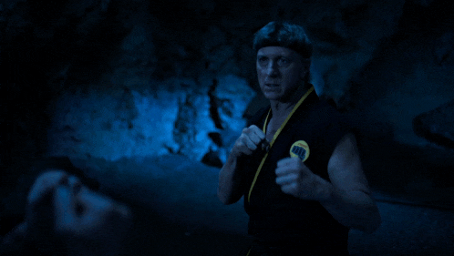 a man in a black karate uniform with a yellow belt has a yellow karate symbol on his chest