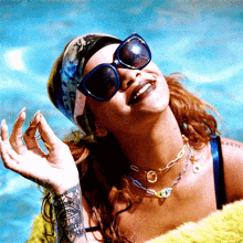 a woman wearing sunglasses and a necklace is smiling in front of a pool