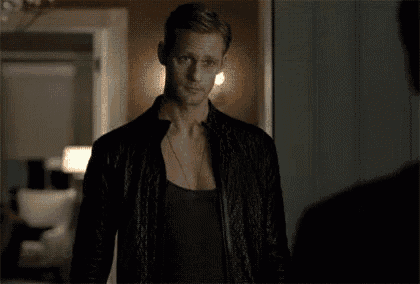 a woman in a black dress is standing in a dark room with her head down .