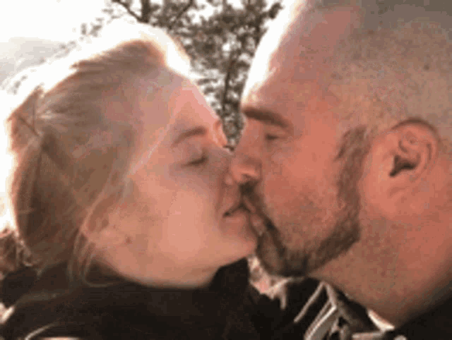 a man with a beard kisses a woman on the nose