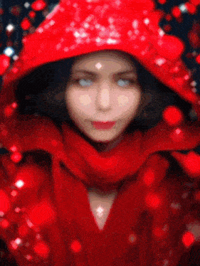 a woman wearing a red hood and scarf with white eyes
