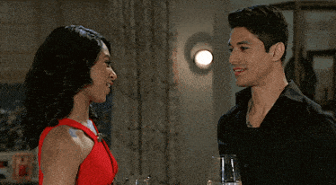 a man and a woman are looking at each other and holding wine glasses