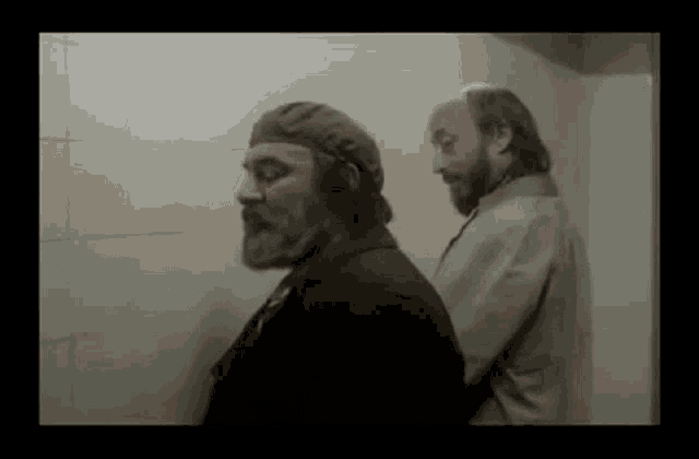 a man with a beard is standing next to another man