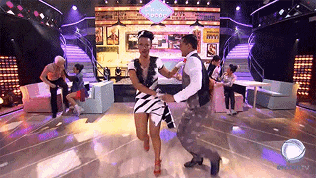 a man and woman are dancing on a stage in front of a sign that says ' popcorn ' on it