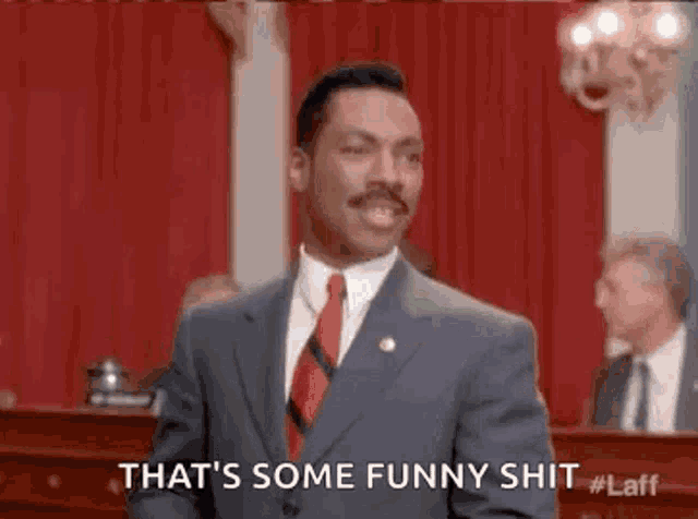 a man in a suit and tie is giving a thumbs up and saying `` that 's some funny shit ''