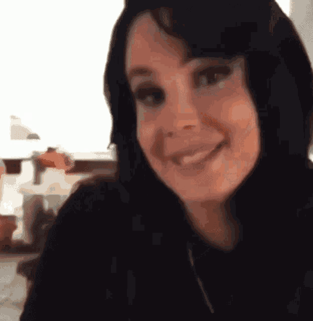 a woman with long black hair is smiling at the camera .