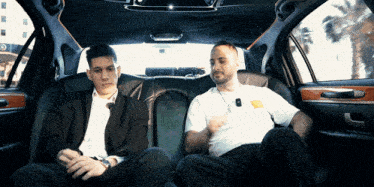 two men are sitting in the back of a limousine