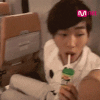 a man is eating a lollipop with a mnet logo in the background