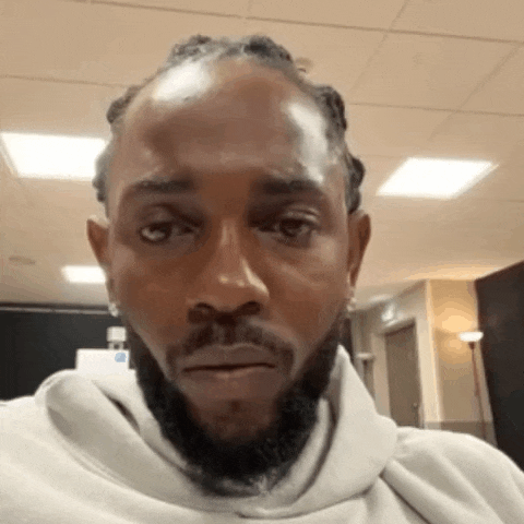 a man with dreadlocks and a beard wears a grey hoodie