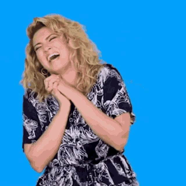 a woman in a black and white dress is laughing with her arms in the air .