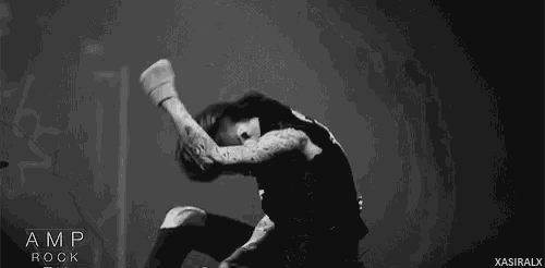 a black and white photo of a man with tattoos on his arms and legs standing on a stage .
