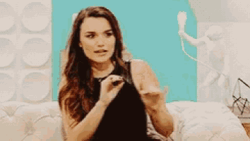 a woman in a black dress is sitting on a couch holding a cell phone