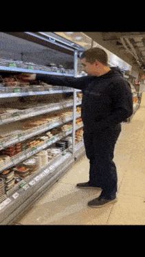 a man in a black hoodie is standing in front of a grocery aisle