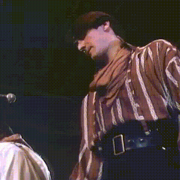 a man in a striped shirt is standing in front of a microphone on a stage .