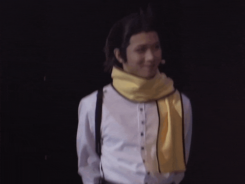 a man wearing a yellow scarf around his neck and suspenders