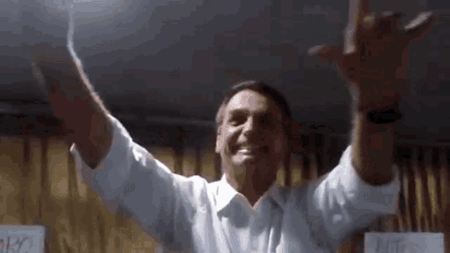 a man in a white shirt is standing with his arms outstretched and smiling .