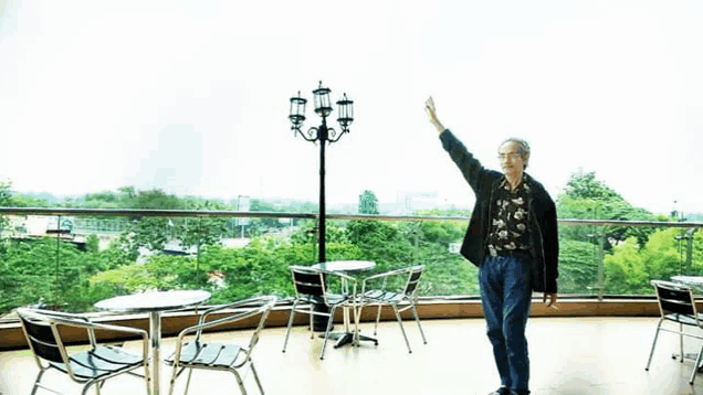 a man standing on a balcony with his hand up