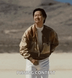 a man in a brown jacket and white pants is standing in a desert and pissing contest .
