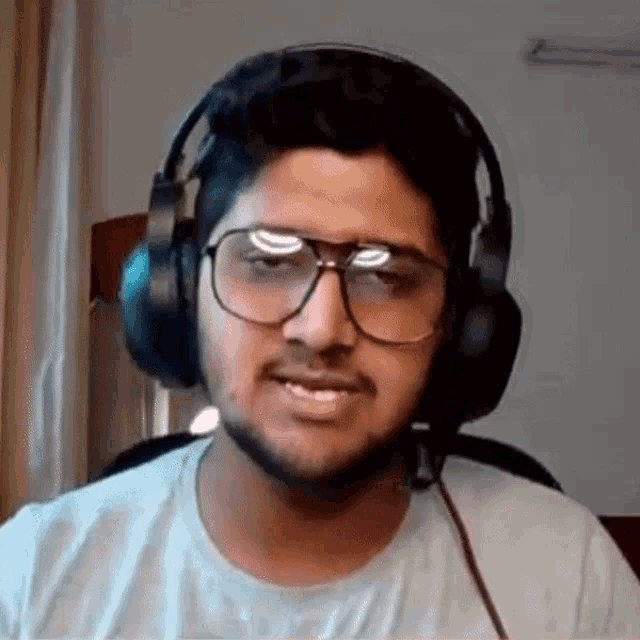 a man wearing headphones and glasses is smiling .